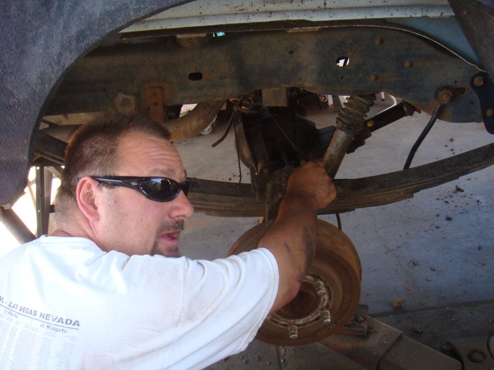 1992 Ford Bronco rear axle assembly with leaf springs and shock absorber, man in sunglasses working on it