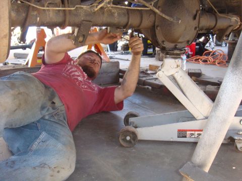 1992 Ford Bronco - Mechanic performs maintenance on the undercarriage of a vehicle, focusing on the rear axle.