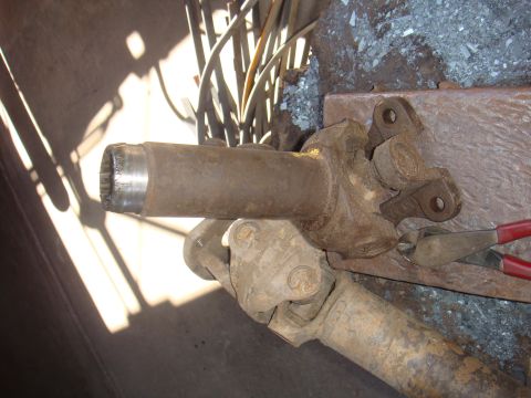 1992 Ford Bronco - Rusty driveshaft part with U-joint and yoke, being held by pliers.