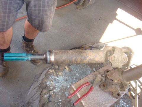 1992 Ford Bronco - A person is working on a driveshaft part, which is resting on a surface with tools nearby tools.