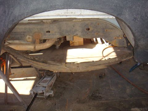 1992 Ford Bronco - Close-up view of a vehicle's rear axle and suspension system, with a jack supporting the frame.