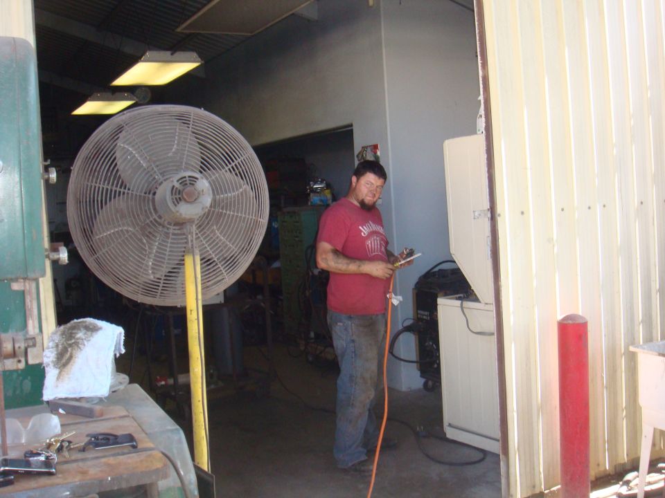 Man standing in a workshop with a large fan and equipment