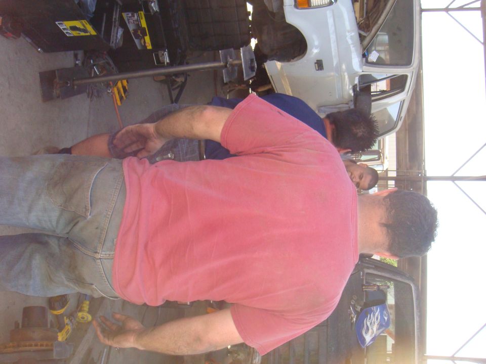 1992 Ford Bronco being worked on by two mechanics in a garage