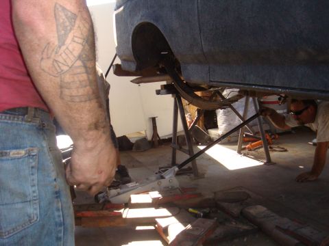 1992 Ford Bronco - Mechanics work on the rear suspension of a vehicle that is elevated on jack stands.