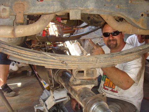 1992 Ford Bronco - Mechanic points to the rear axle and leaf spring assembly of a vehicle.