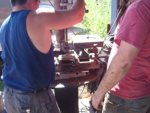 1992 Ford Bronco - Men are working on a drill press in an outdoor setting with greenery in the background.
