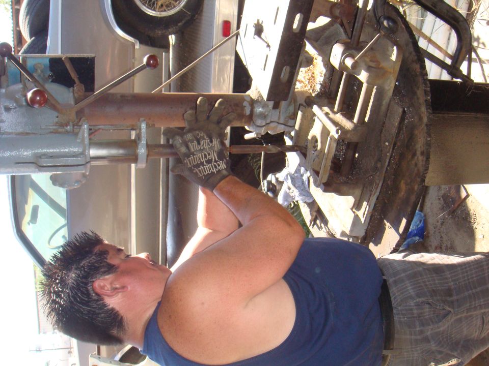 Person working on vehicle axle with Supermotors logo visible