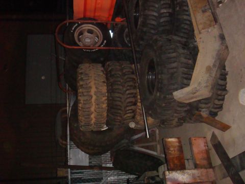 1992 Ford Bronco - Several large off-road tires are stacked up, some appear to be used.