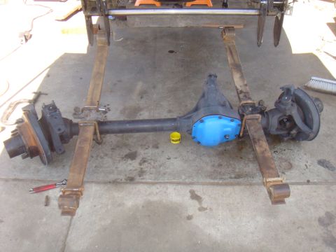 1992 Ford Bronco - Vehicle axle assembly with a blue differential cover is shown on a concrete surface.