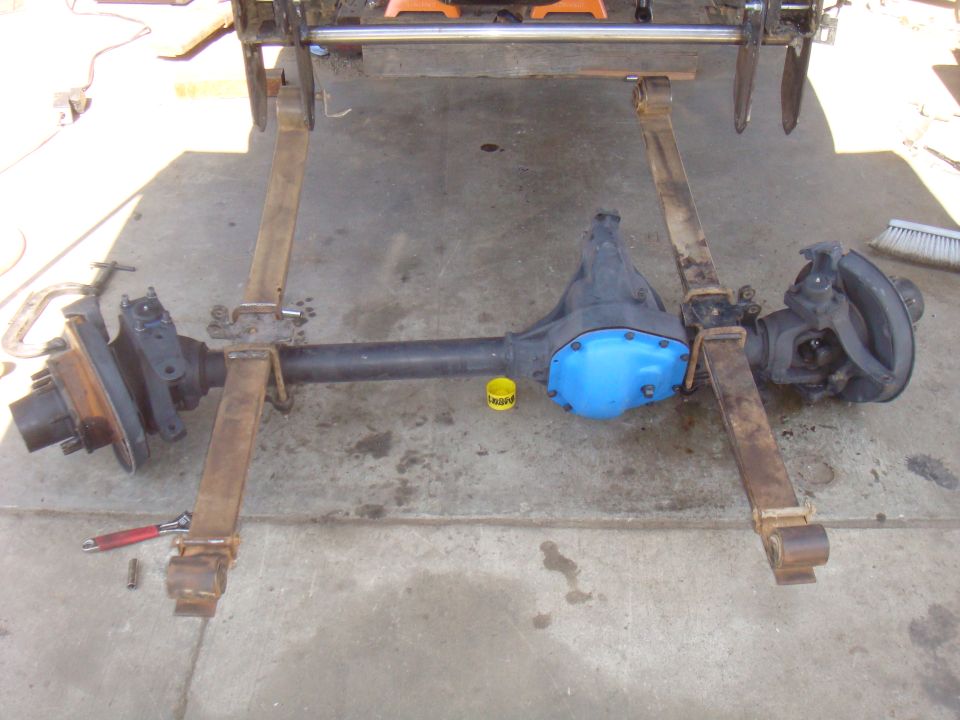 Vehicle axle assembly with blue differential cover, supported by metal stands on concrete
