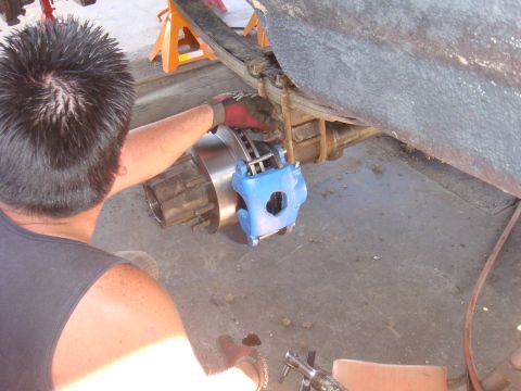 1992 Ford Bronco - Mechanic installing a new brake caliper and rotor on a vehicle's rear axle.