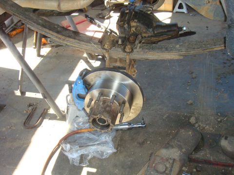 1992 Ford Bronco - Close-up of a vehicle's rear axle assembly, showing a new brake rotor and caliper during a repair.