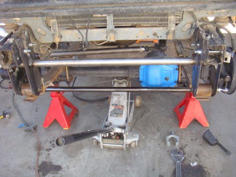 1992 Ford Bronco - The rear axle assembly of a vehicle is supported by jack stands and a floor jack during maintenance.