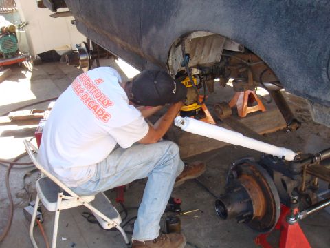 1992 Ford Bronco - Mechanic works on the rear axle of a vehicle, with suspension components and tools laid out.