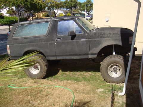 Black Ford Bronco with lifted suspension and large tires parked on grass