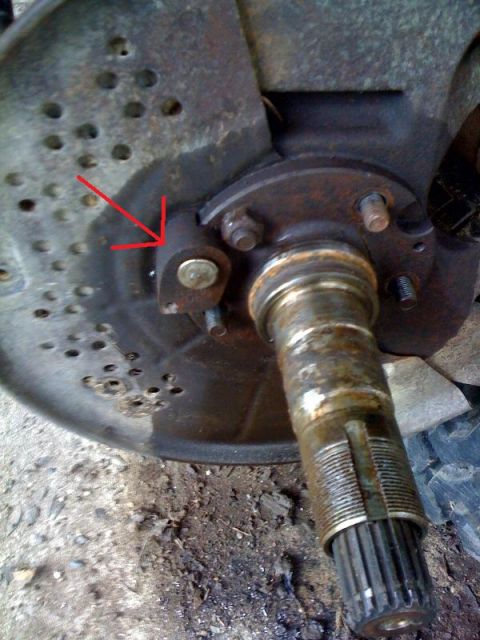 1995 Ford Bronco - Close-up view of a vehicle's brake rotor and hub assembly, with a red arrow indicating a specific bracket.