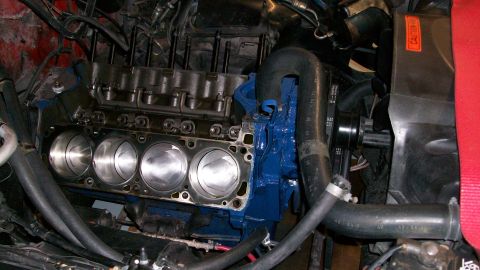 1973 Ford Ranchero - Close-up view of an engine block with pistons, blue painted components and black hoses.