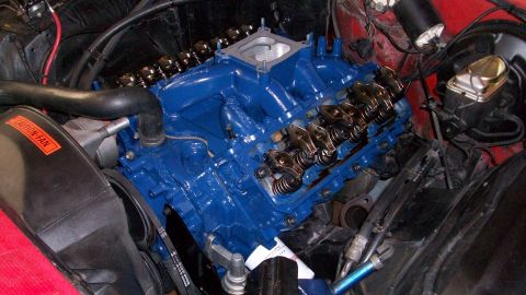 1973 Ford Ranchero - Close-up of a blue V8 engine, likely undergoing maintenance or modification, with a "CAUTION-FAN" sticker visible on the fan shroud.