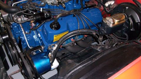 1973 Ford Ranchero - The engine bay shows a blue V8 engine with various hoses and wiring, including a prominent brake fluid reservoir.