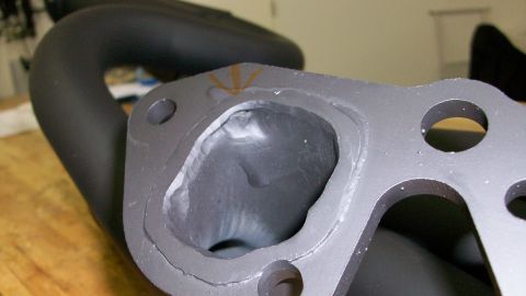 1973 Ford Ranchero - This is a close-up view of a vehicle's exhaust manifold port, showing the rough casting and a portion of the exhaust pipe.