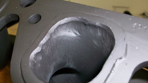 1973 Ford Ranchero - This is a close-up view of a rough-cast engine cylinder head port, with visible casting imperfections and some markings.