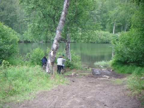 1998 Jeep Cherokee - Two dirt bikes are parked on a muddy path leading to a lake, surrounded by trees and greenery.