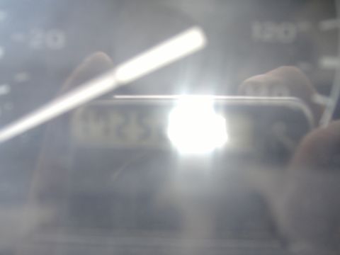 1995 Ford F-150 - A close-up of a vehicle's dashboard gauge cluster, with a bright reflection obscuring most of the details.