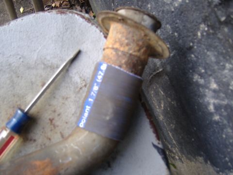1995 Ford F-150 - A close-up of a rusted pipe with measurement tape and a screwdriver, suggesting a repair or part replacement.