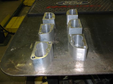 1993 Ford Taurus - Several machined aluminum parts are laid out on a workbench, with a Ford logo visible in the background.