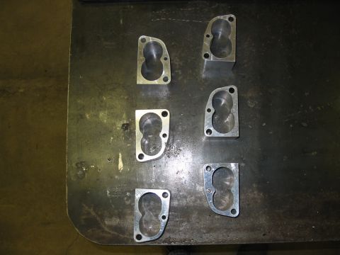 1993 Ford Taurus - Several throttle body spacers are laid out on a workbench, ready for installation.