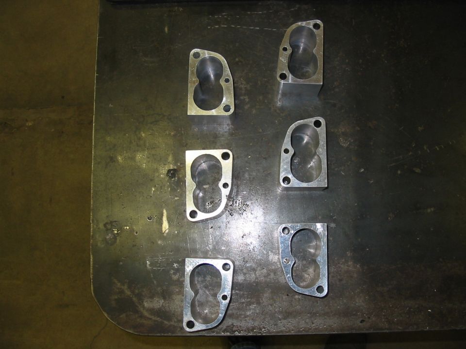 Six throttle body spacers on a metal surface