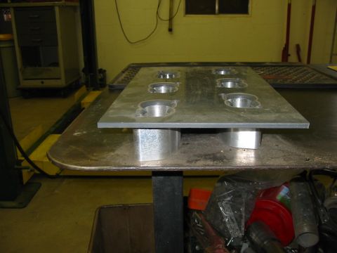 1993 Ford Taurus - Metal plate with circular cutouts, likely a jig or fixture, resting on a workbench.
