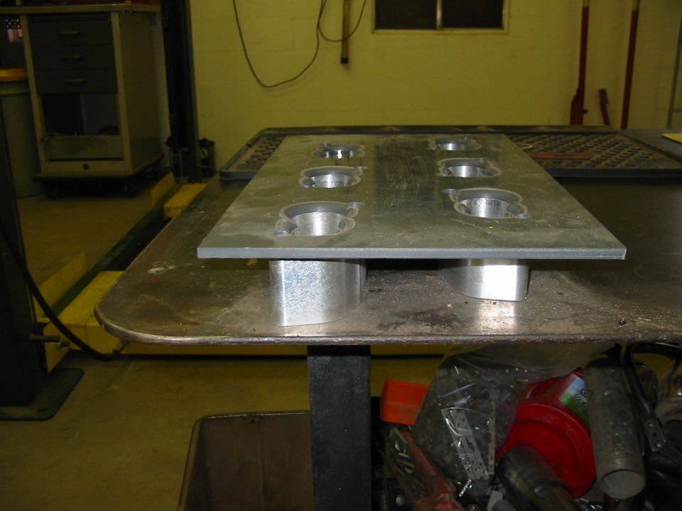 Metal plate with eight circular cutouts, raised on metal blocks