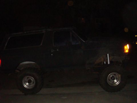 Dark 1992 Ford Bronco side view, lifted with large tires, visible Supermotors logo