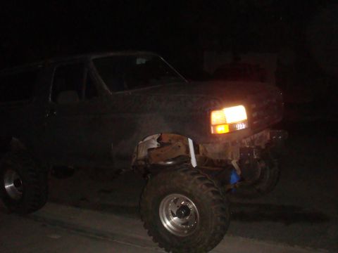 Dark 1992 Ford Bronco with lifted suspension and large tires, front passenger side visible