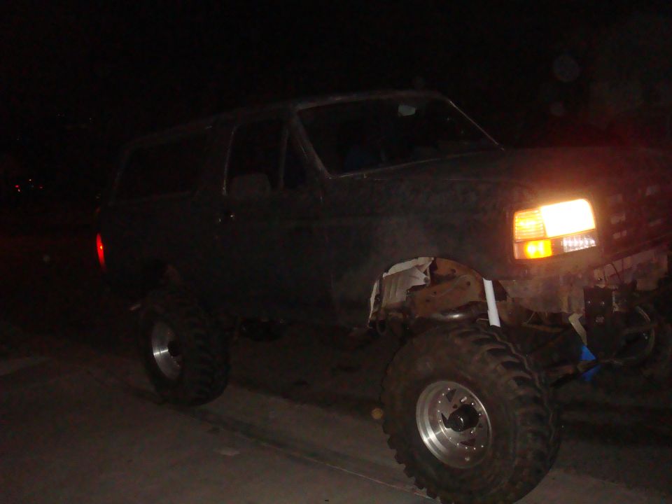 Dark SUV with lifted suspension and large tires, front right wheel visible