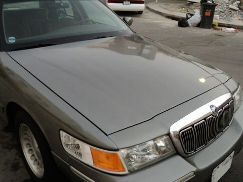 2001 Mercury Grand Marquis - The front of a gray 2001 Mercury Grand Marquis is visible, showing its distinctive grille and headlights.