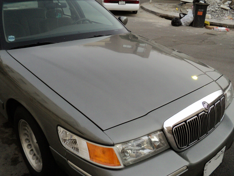 Hood and chrome grille of a gray-green Mercury Grand Marquis with Mercury emblem