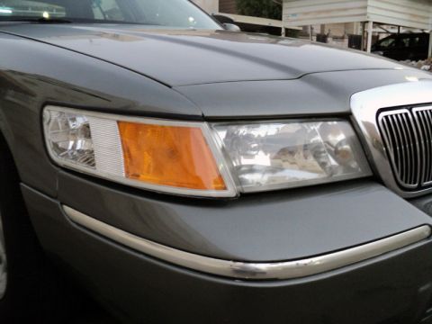 2001 Mercury Grand Marquis - Front corner view of a gray 2001 Mercury Grand Marquis, showing the headlight, turn signal, and chrome grille.