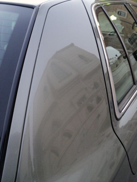 2001 Mercury Grand Marquis - The reflection on the car's paint shows architectural details of a building.