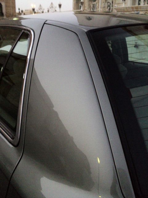 2001 Mercury Grand Marquis - Close-up of a silver sedan's rear pillar and window trim, showing a chrome accent strip.
