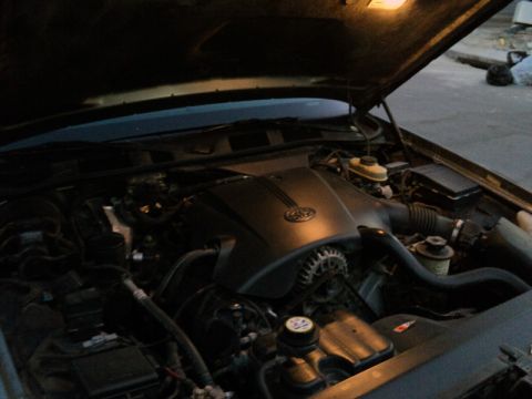 2001 Mercury Grand Marquis - The engine bay of a 2001 Mercury Grand Marquis is visible with the hood open, showing the engine cover with a Ford logo.