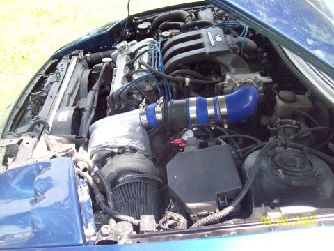 1995 Ford Probe - The engine bay of a blue car is shown, a turbocharger and custom intake piping.