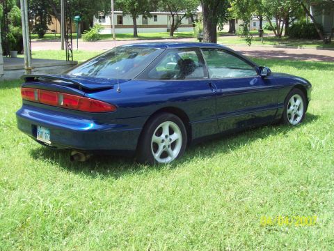 1995 Ford Probe - A blue 1995 Ford Probe is parked on a grassy lawn with trees and houses in the background.