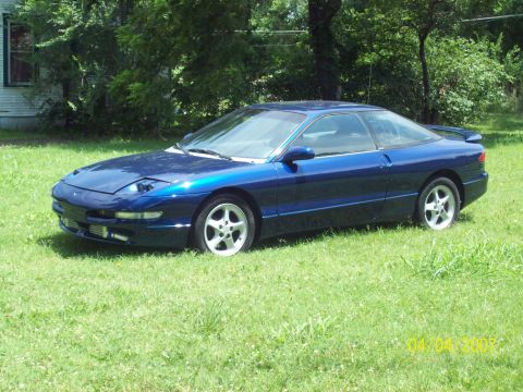 1995 Ford Probe - A blue 1995 Ford Probe is shown parked on a grassy lawn with trees in the background.