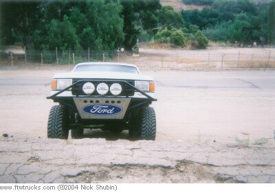 1988 Ford Bronco - This modified Ford truck features an aftermarket bumper with auxiliary lights and a prominent Ford logo.