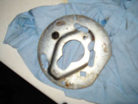 1967 Ford F-250 - Metal distributor mounting plate with a central cutout and mounting holes, placed on a blue cloth.