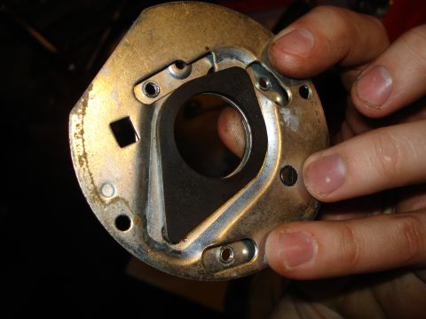 1967 Ford F-250 - A person holds a metal distributor base plate, showing its internal components and mounting holes.