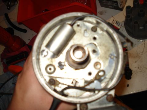 1967 Ford F-250 - A mechanic's hand holds a disassembled distributor, revealing internal components.