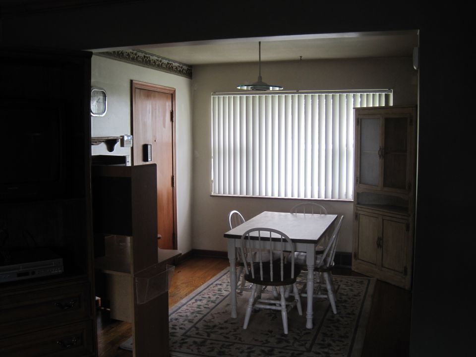 Dining room with a table, four chairs, a hutch, and vertical blinds covering a window